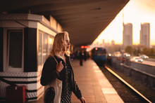Thoughtful Young Woman Waiting For Train At Subway Station At Sunset