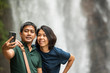 © Cavan Images - couple are taking a selfie on their smart phone at Ramboda Waterfall