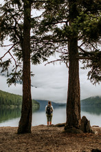 Woman Hiker With Backpack Framed By Trees At Bowman Lake, Montana