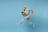 Fototapeta  - Side view of excited traveler tourist man in yellow clothes with photo camera isolated on blue background. Male passenger traveling abroad on weekend. Air flight journey concept. Jumping like running.
