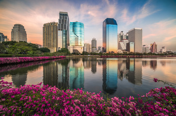 Wall Mural - Lake with Purple Flowers in City Park under Skyscrapers at Sunset. Benjakiti Park in Bangkok, Thailand