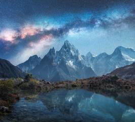 Wall Mural - milky way over snowy mountains and lake at night. landscape with snow covered high rocks and starry 
