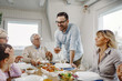 © Drazen - Happy man proposing a toast wo his family in dining room.