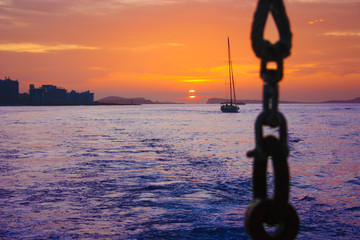 Wall Mural - romantic orange sunset over the water of the sea and the chain or anchor of a boat to the side