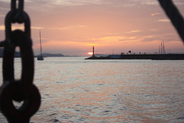 Wall Mural - romantic orange sunset over the water of the sea and the chain or anchor of a boat to the side
