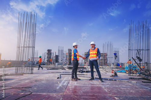 Fotografie, Obraz Architect and engineer construction workers shaking hands while working at outdoors construction site