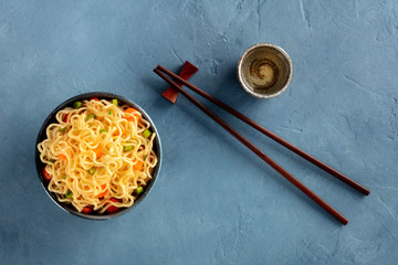 Instant noodles bowl with carrot and scallions, top shot with chopsticks and sake