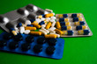 Different tablets, pills, medications drugs on green background
