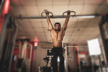 Strong man doing pull ups in gym