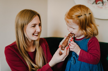 Portrait of happy young mother and daughter child girl are eating tasty cake after dinner, isolated in restaurant. Two sisters eat cupcakes together. Happy loving family.