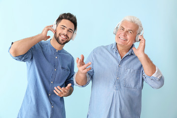 Poster - Young man and his father listening to music on color background