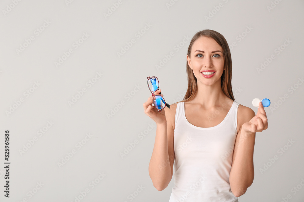 Woman with contact lenses and glasses on light background