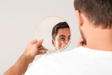 Wall Mural - Man putting contact lenses in eyes on light background