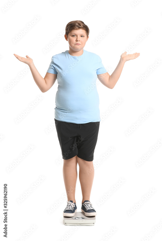 Overweight boy standing on scales against white background