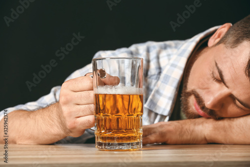 Fotografía Drunk man with beer at table. Concept of alcoholism
