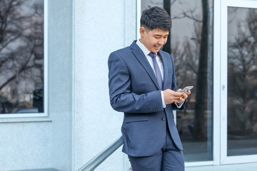 Poster - Young Asian businessman with mobile phone outdoors