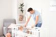 © Pixel-Shot - Young man suffering from postnatal depression near bed with baby at home