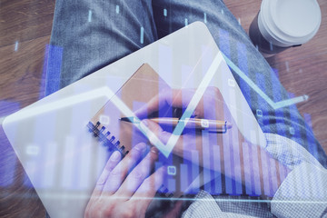 Double exposure of man doing notes of stock market with forex graph.