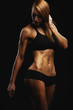 © Georgii - Portrait of a fit young woman posing wearing a sports bra against black background. Determined athlete in the studio. Copy space, black background, sports banner.