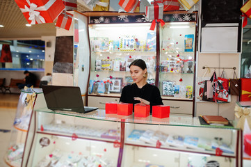 Portrait of young caucasian female woman seller hold red gift boxes. Small business of candy souvenirs shop.