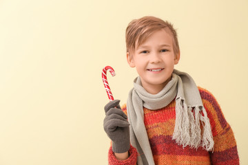 Canvas Print - Cute little boy in winter clothes and with candy cane on color background