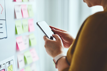 woman with mobile phone planning website on whiteboard