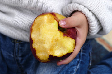 Wall Mural - a boy eating an apple, the little boy is eating an apple in his hand,