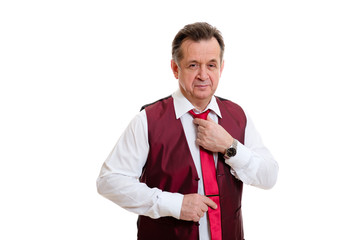 Portrait of 55-60 years old senior man. Smart and old businessman in marsala vest and white shirt. He correct his red tie on white isolated background