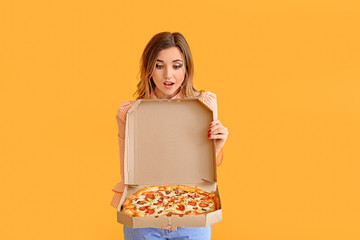 Portrait of surprised young woman with tasty pizza on color background