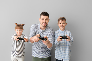 Wall Mural - Father and his little children playing video games on grey background