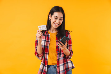 Wall Mural - Image of happy attractive woman holding credit card and using cellphone