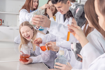 A young student of a chemical faculty rejoices at the results of the experiment. A group of students in a chemistry lab.