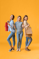 Sticker - Young women with mobile phone and shopping bags on color background