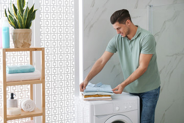 Wall Mural - Happy man with clean clothes near washing machine in bathroom. Laundry day