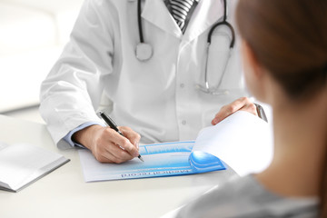 Wall Mural - Doctor consulting patient at desk in clinic, closeup