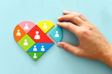 Wall Mural - image of heart shape tangram puzzle blocks with people icons over wooden table ,human resources and management concept