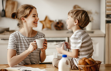 Wall Mural - preparation of family breakfast. mother and child son cut bread  and eat cookies with milk in morning