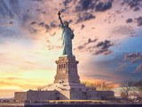 Fototapeta  - famous statue of  liberty and dramatic sky at sunset with orange colors. Travel concept