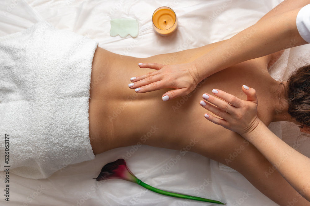 top view professional masseuse performing with hand back massage to young woman client in wellness spa center, beauty photo concept and atmosphere of calm and relaxation