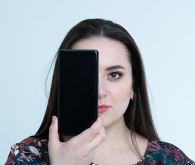 Wall Mural - Charming girl covers her face by smartphone