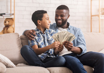 Wall Mural - Happy Afro Dad And Preteen Son With Dollar Cash At Home