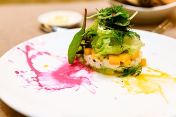 Crab Tian with mango and avocado, herb and vegetables salad with sauce on plate, starter or appetizer at a fine dining restaurant