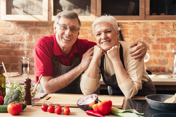 Wall Mural - Portrait of smiling aged couple posing in kitchen