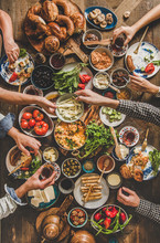 Turkish Breakfast Table. Flat-lay Of Peoples Hands Taking Pastries, Vegetables, Greens, Olives, Cheeses, Fried Eggs, Jams, Honey, Tea In Copper Pot And Tulip Glasses Over Wooden Background, Top View