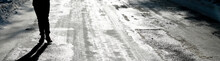 The Icy Road And The Silhouette Of The Legs Of A Man Walking Along It. Selective Focus. Hazard Concept Ice-crusted Ground.