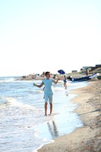  Handsome Boy In Shorts And A T-shirt Teenager Launches A Kite On The Sky On The Seashore In Summer