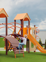 Wall Mural - happy boy climbing into colorful activity tower on the playground, children development and entertainment, playground equipment