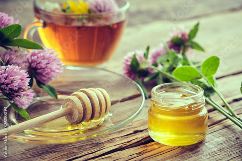 Photographie Clover flowers, healthy, herbal tea cup, honey jar and wooden dipper for honey on table