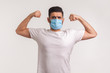 Man in hygienic mask showing strength and immunity to recover from contagious disease, airborne respiratory illness such as flu, coronavirus 2019-nCoV. indoor studio shot isolated on white background