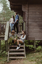 Full Length Of Sibling Sitting On Steps While Parents Standing In Porch